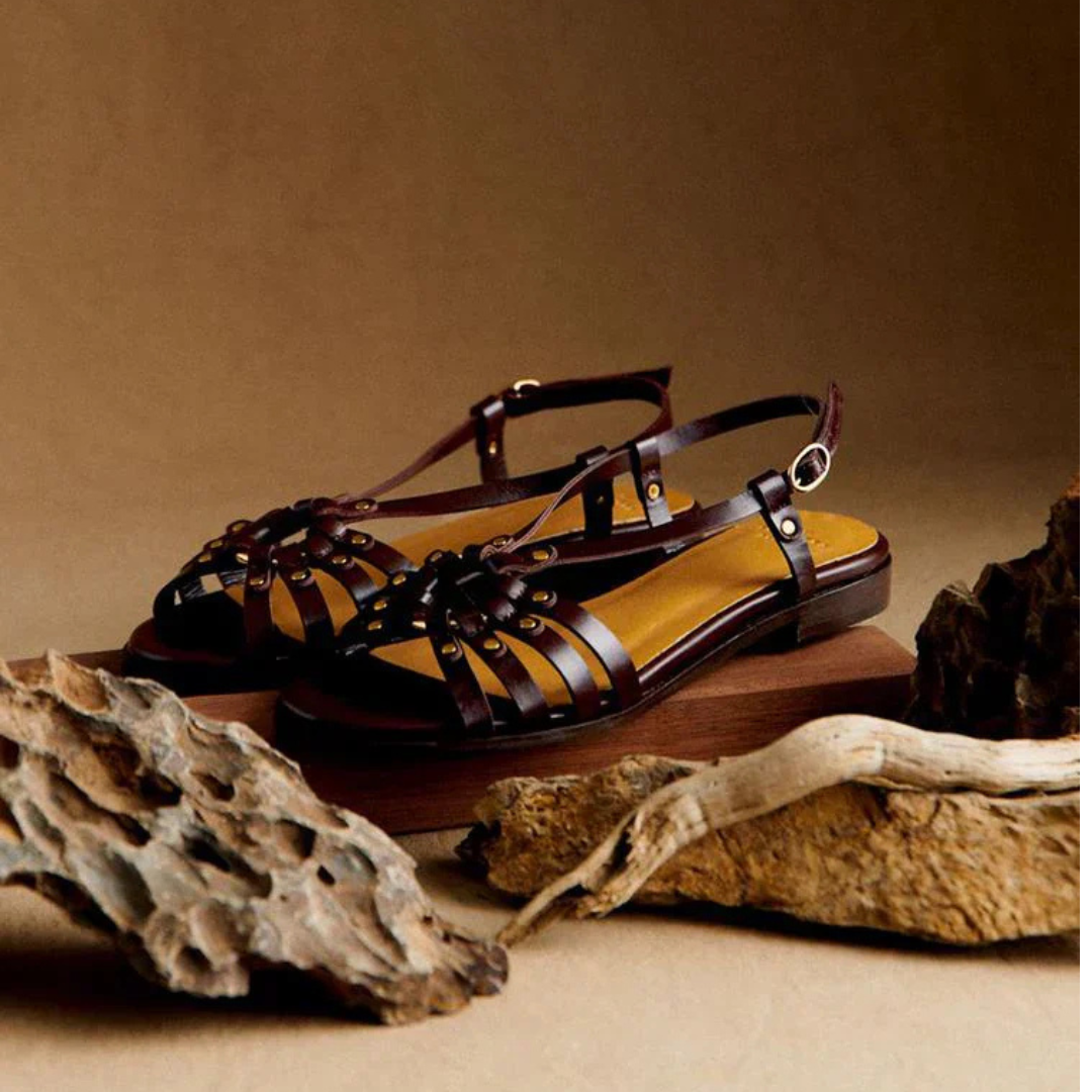 Sandalias con tachuelas metálicas y grabados en color marrón oscuro.